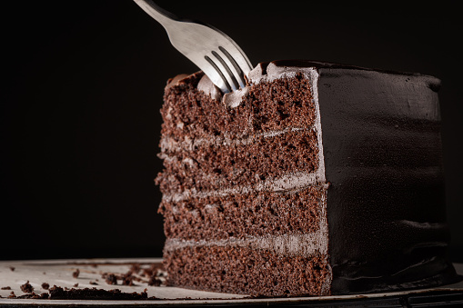 Closeup photo of a delicious slice of chocolate cake on a black background.