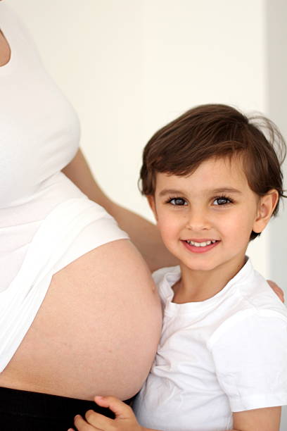 istock boy holding mother's pregnant belly 178042792