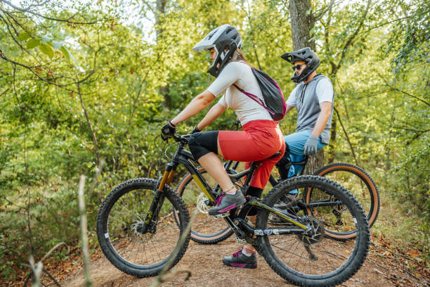 istock Man and woman riding mountain bikes through the forest 1780442573