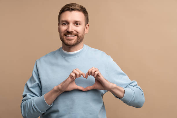 istock Feeling happy in love smiling man making sign heart shape look at camera isolated studio background 1780448397