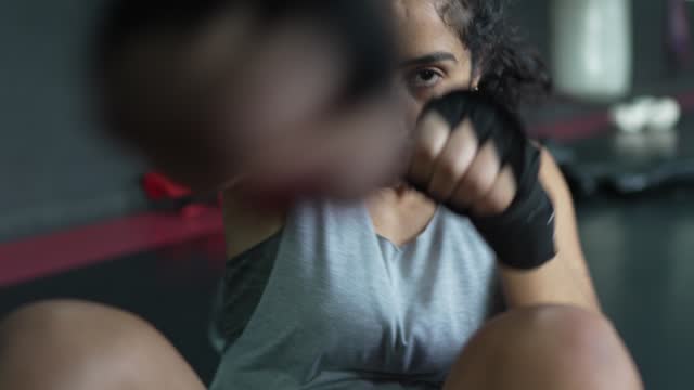 Portrait of a mid adult woman doing push-ups and punching at box gym