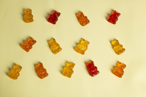 Colorful gummy vitamins, gummy bears on yellow backgruond, background concept