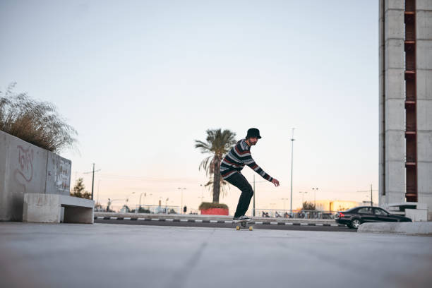 istock caucasian guy in striped pullover sneakers having fun on a skateboard in the city at sunset on a clear day 1780465726