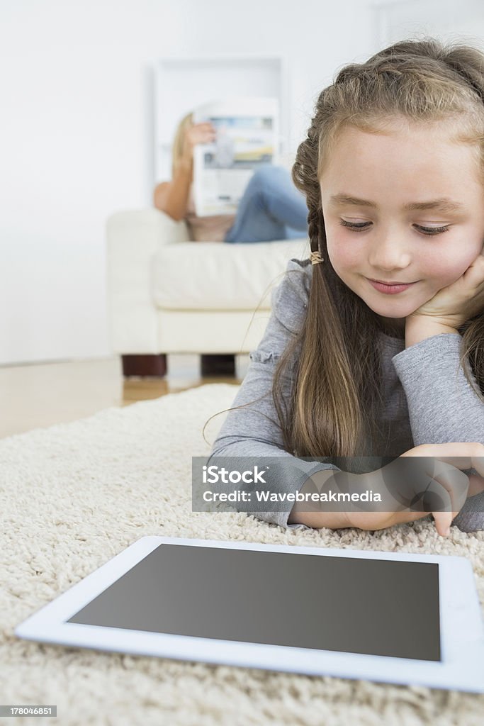 Jeune fille à l'aide de tablette avec sa mère lire le journal - Photo de Assis libre de droits