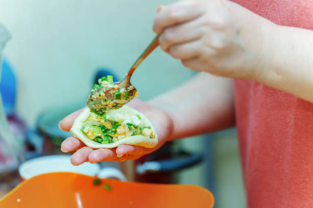 istock Hands putting egg filling and green onions into a pie using a metal spoon 1780469422
