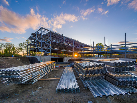 Construction site with steel flooring in front of a  partially erected building at sunset