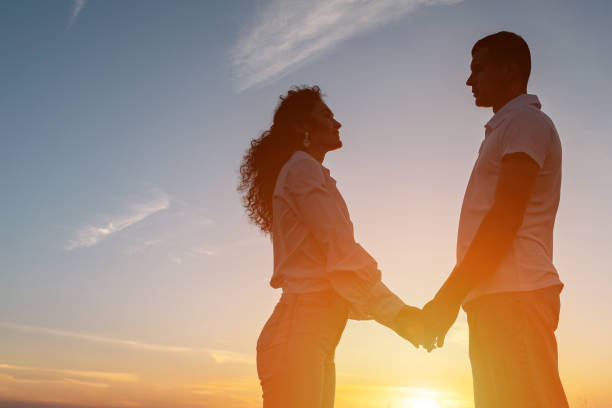 istock Loving couple looks at each other against sky with sunset 1780484865