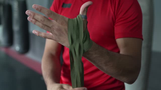 Close-up of a man putting elastic bandage on hands at boxe gym