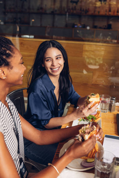istock Two businesswomen eating hamburger at lunch break 1780490467