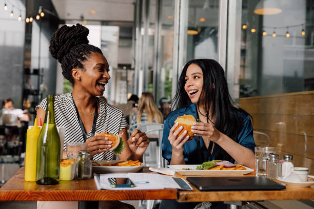 dos mujeres de negocios comiendo hamburguesa en la pausa del almuerzo - dining burger outdoors restaurant fotografías e imágenes de stock