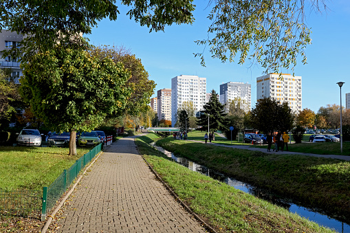 Warsaw, Poland - October 29, 2023: A group of apartment blocks in the distance behind a narrow canal in the Goclaw housing estate in the Praga-Poludnie district.