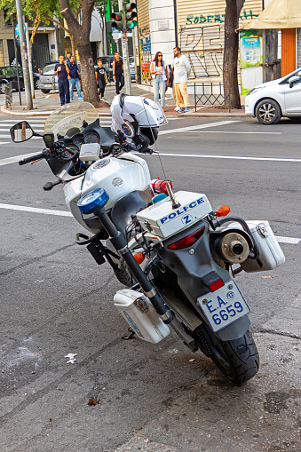 Thessaloniki, Greece - October 22, 2023: Fully equipped Greek police motorcycle on a pavement on urban street in Thessaloniki with people standing in a back.