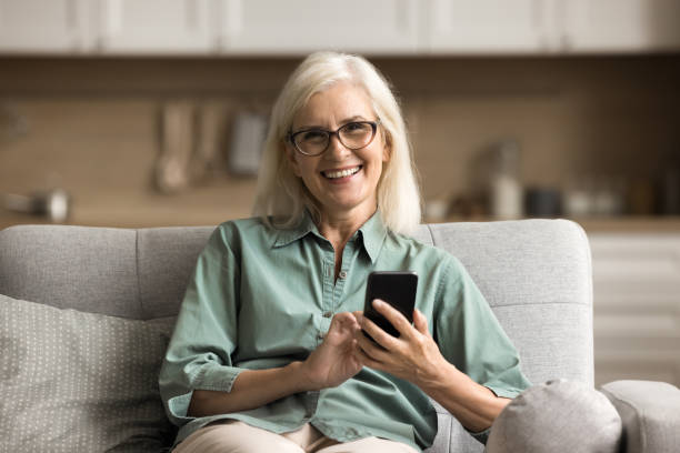 istock Happy blonde senior woman in stylish glasses using application 1780510373
