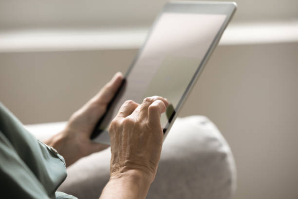 Hands of mature woman holding tablet computer, touching screen