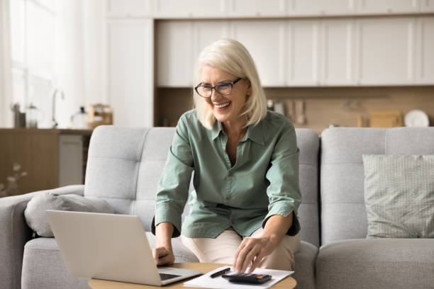 istock Cheerful blonde retired old woman using financial application on laptop 1780510952