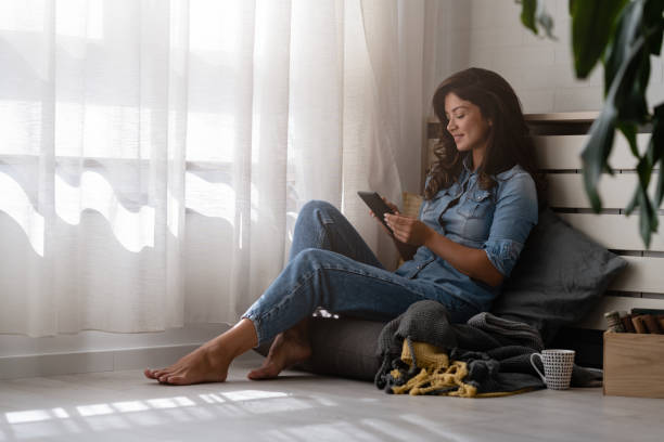 istock Handsome young woman reading an e-book, drinking coffee at home 1780515657