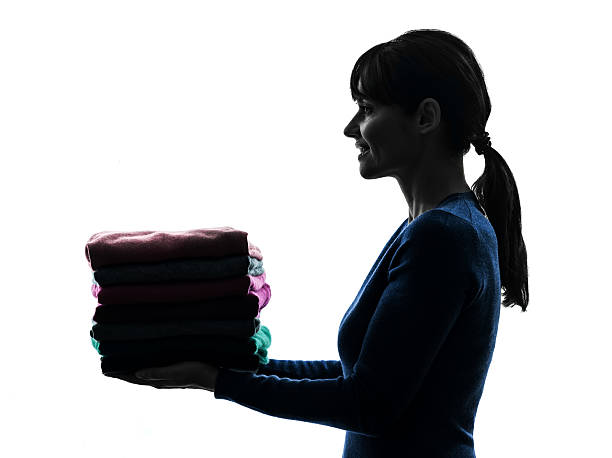woman maid housework holding sweater pile silhouette one caucasian woman maid holding sweater pile cleaning in silhouette studio on white background custodian silhouette stock pictures, royalty-free photos & images