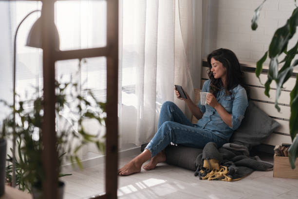 istock Handsome young woman reading an e-book, drinking coffee at home 1780518952