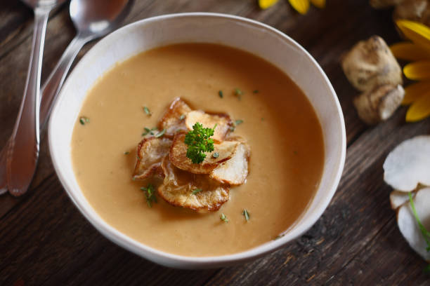 Jerusalem artichoke soup and chips on wooden background