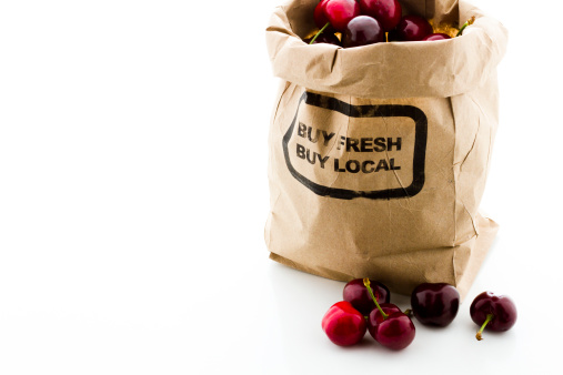 Brown bag of fresh cherries from the local farmers market.