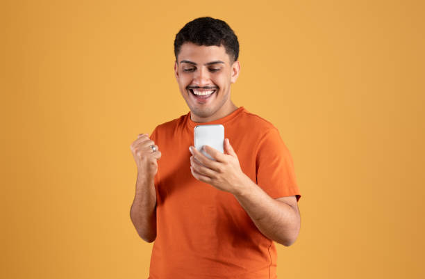 istock Digital success. Happy brazilian man using cellphone and gesturing yes celebrating online win, reading great news 1780537171
