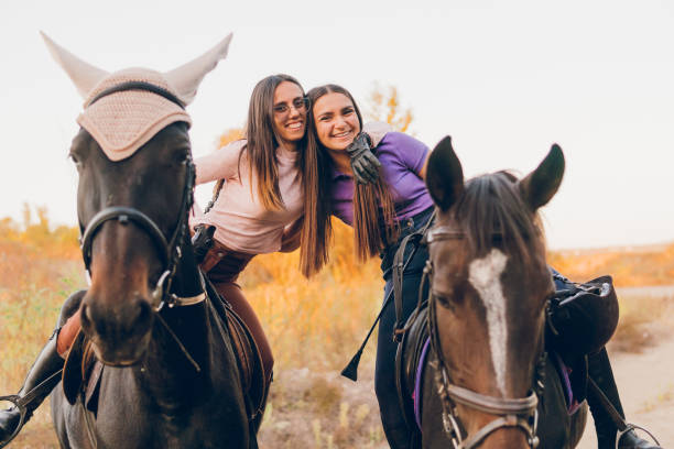 Smiling women riding horses and talkingSmiling women enjoying with their horses