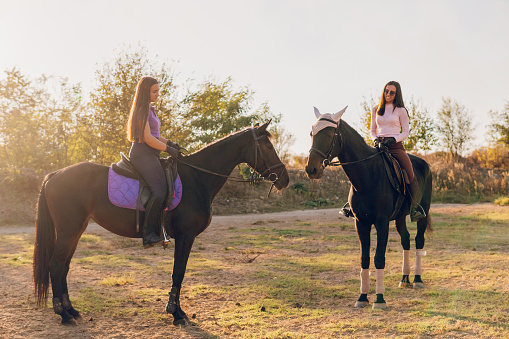 Smiling women riding horses and talking