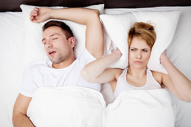 Snoring man problem. Snoring man and young woman. Couple sleeping in bed. sleep apnea photos stock pictures, royalty-free photos & images