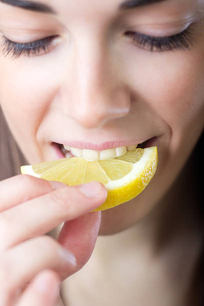 istock young beautiful woman eating lemon 178054335
