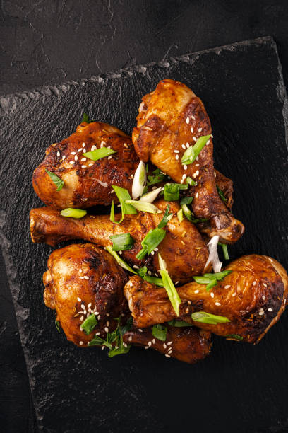 istock Chicken drumsticks with sesame seeds, Asian cooked chicken, black background vertical photo 1780545836