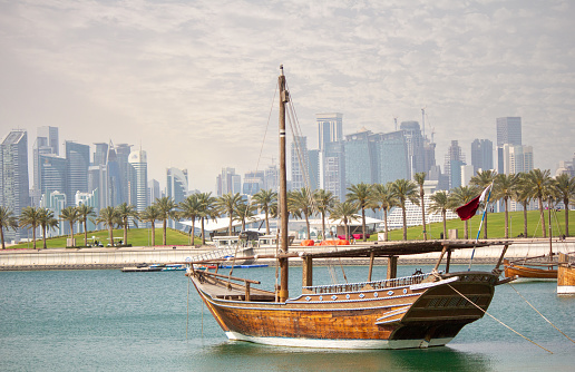 Qatar skyline along qatar traditional dhow in the foreground.