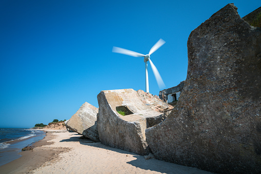 Old abandoned fortifications at Baltic sea coast near Liepaja,  Latvia. Large wind turbine in the background
