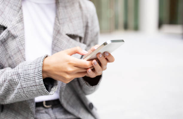 istock Unrecognizable businesswoman holding modern smartphone using mobile business application outdoors 1780553601
