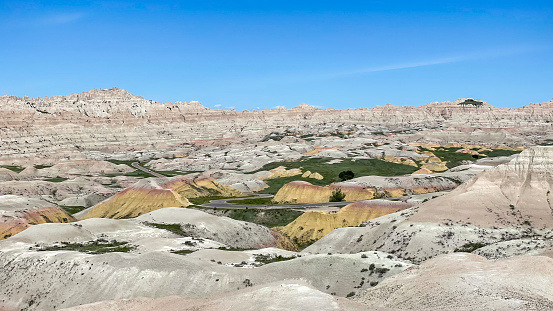 Yellow Mounds from Conata Basin Overlook, Badlands National Park, South Dakota, USA. A road winds its way through the mounds.