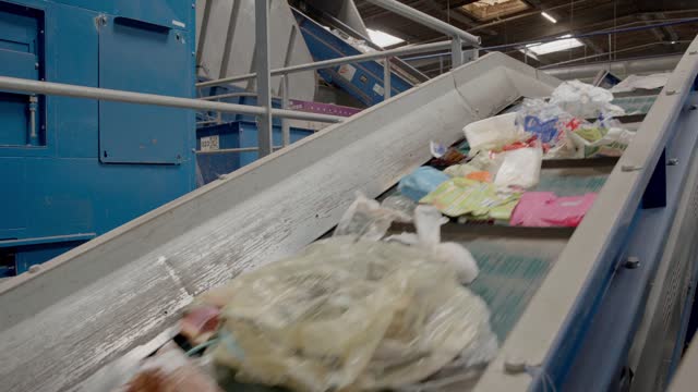 Sorting conveyor belt moving upwards caring out the waste materials, mostly paper and plastic. Efficiency and dedication in responsible waste management concept.