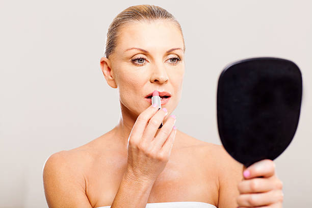 istock middle aged woman putting lip stick 178060522