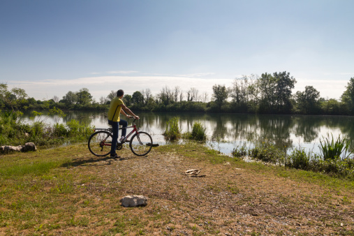 man with bicycle standing in front of riverSee other Cycling images and videos on
