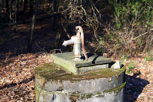 Hand Pump on top of Well An old hand pump, on top of a well. Showing handle in down position, with moss growing on top of the well. old fashioned well hand pump stock pictures, royalty-free photos & images