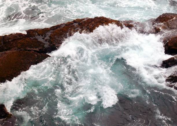 A stunning shot of an ocean wave crashing against the rocks in the sea, creating a spectacular display of white foam and mist