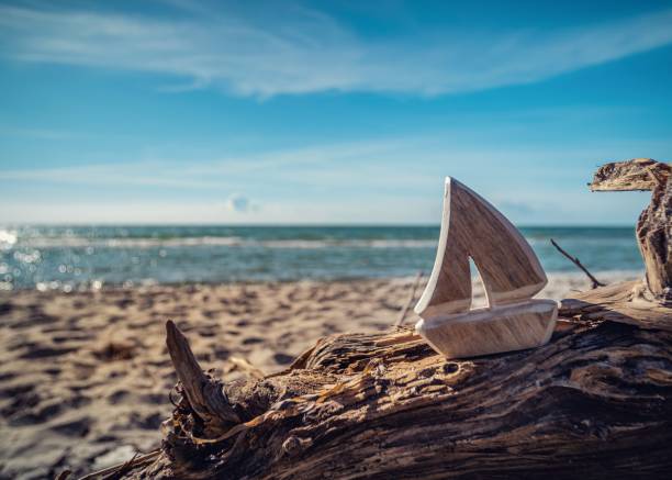 giocattolo della nave di legno su tronco alla spiaggia con i cieli blu - logboat foto e immagini stock