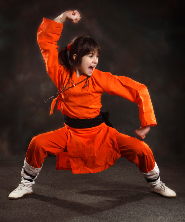 girl in an orange suit performs the form of martial arts with a shout