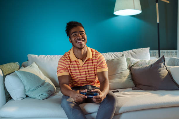 istock Young African American man playing video games at home 1780656747