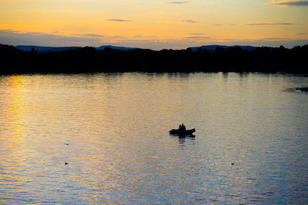 Two people om a rubber dinghy at night.
