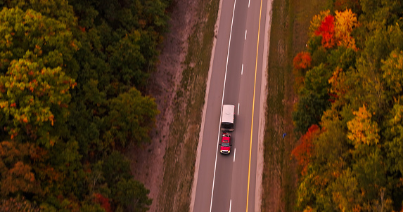 Aerial still of a truck passing on U.S. Route 31 in Michigan, at dawn in Fall.