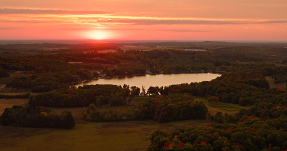 Aerial still of farmland and a lake near Shelby, a village in Oceana County in Michigan, at dawn in Fall.