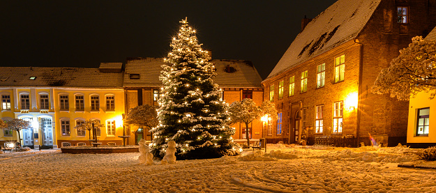 Snowmans near Christmas tree.View of market square with decorated Christmas tree covered with snow on winter day. Christmas atmosphere at the town hall market of Schleswig,Schleswig-Holstein,Germany.