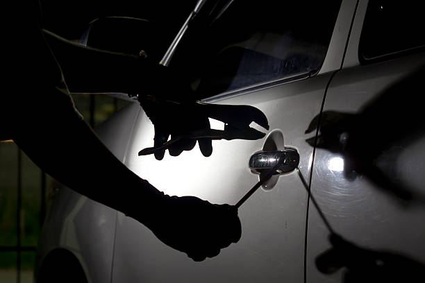автоугонщик используя инструмент для отдыха в автомобиле. - car stealing thief car thief стоковые фото и изображения