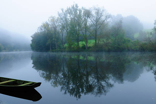 istock Beautiful misty morning lake with boat and tree reflection 178069328