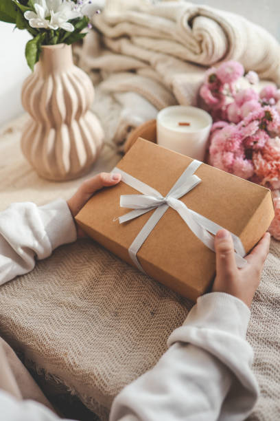 istock Gift box in hands with flowers at home 1780695186