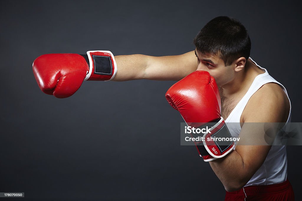 Attack Portrait of young man in red boxing gloves fighting in isolation Active Lifestyle Stock Photo